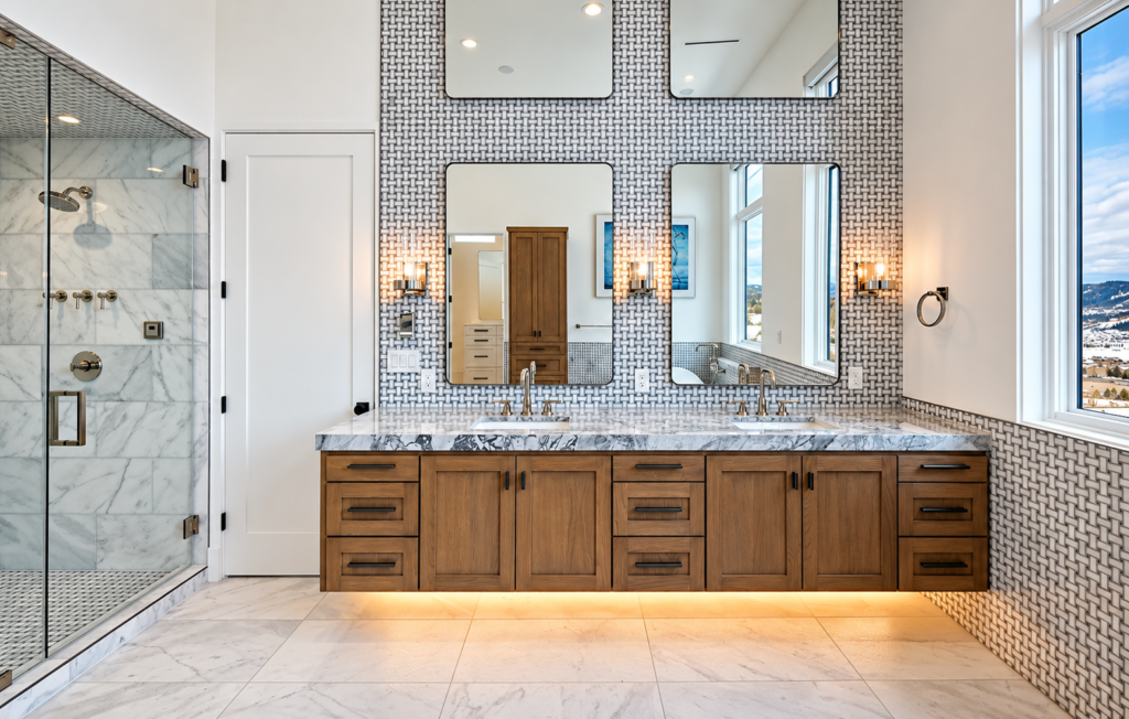 Luxury primary bathroom in Steamboat Springs featuring a floating wood double vanity, marble countertops, patterned tile backsplash, and glass-enclosed shower.